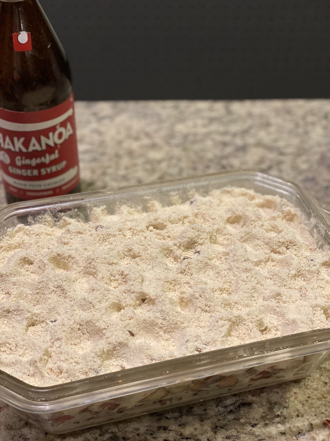 Container of food with a bottle of Kakanoa Gingerale in the background on a countertop. Rhubarb & Ginger Crumble