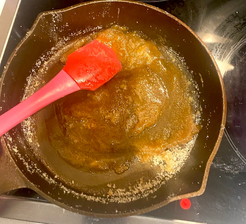 Brown sugar mixture in a cast iron skillet with a red spatula