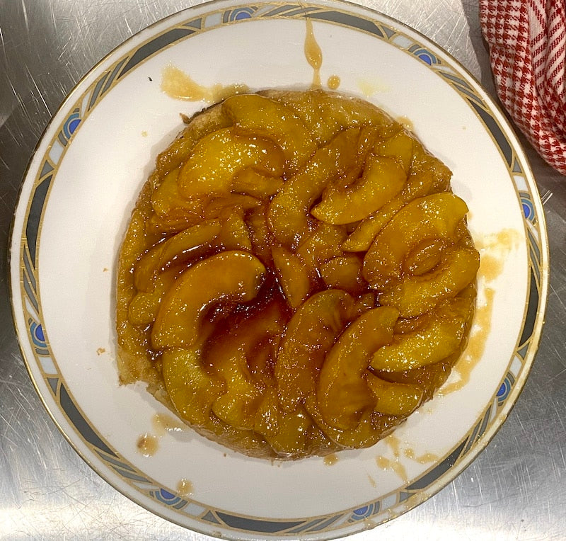 Apple tart on a decorative plate with a metal surface in the background