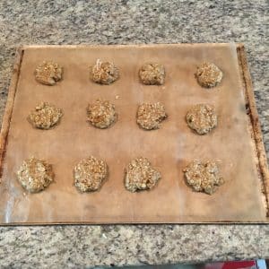 Baked cookies on a baking sheet with a wooden handle on a granite countertop.