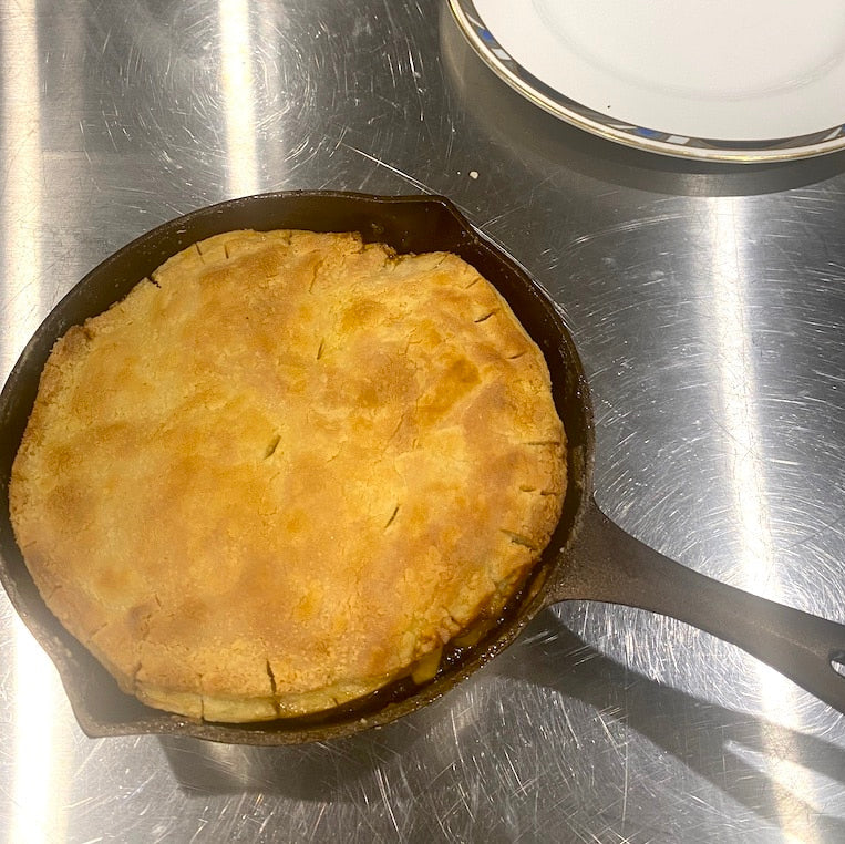 Baked pie in a cast iron skillet on a metallic surface