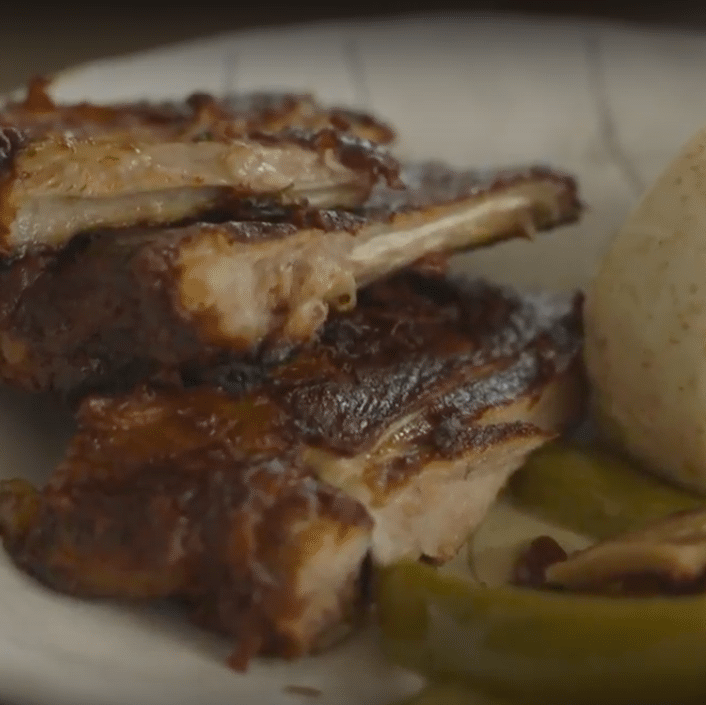 Plated dish with ribs, green pepper, and mashed potato on a white plate.