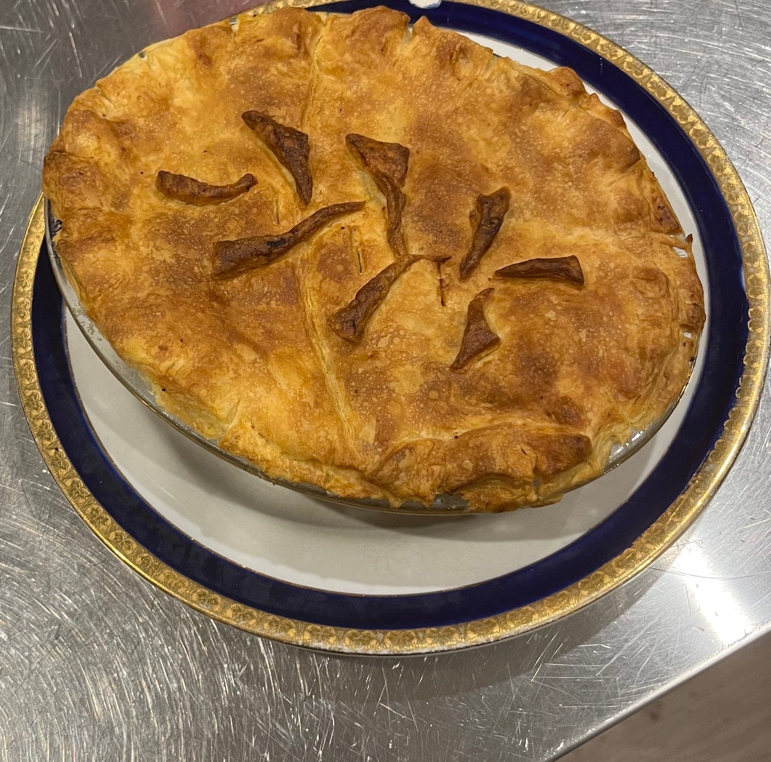 Baked pie with a decorative crust on a metal surface