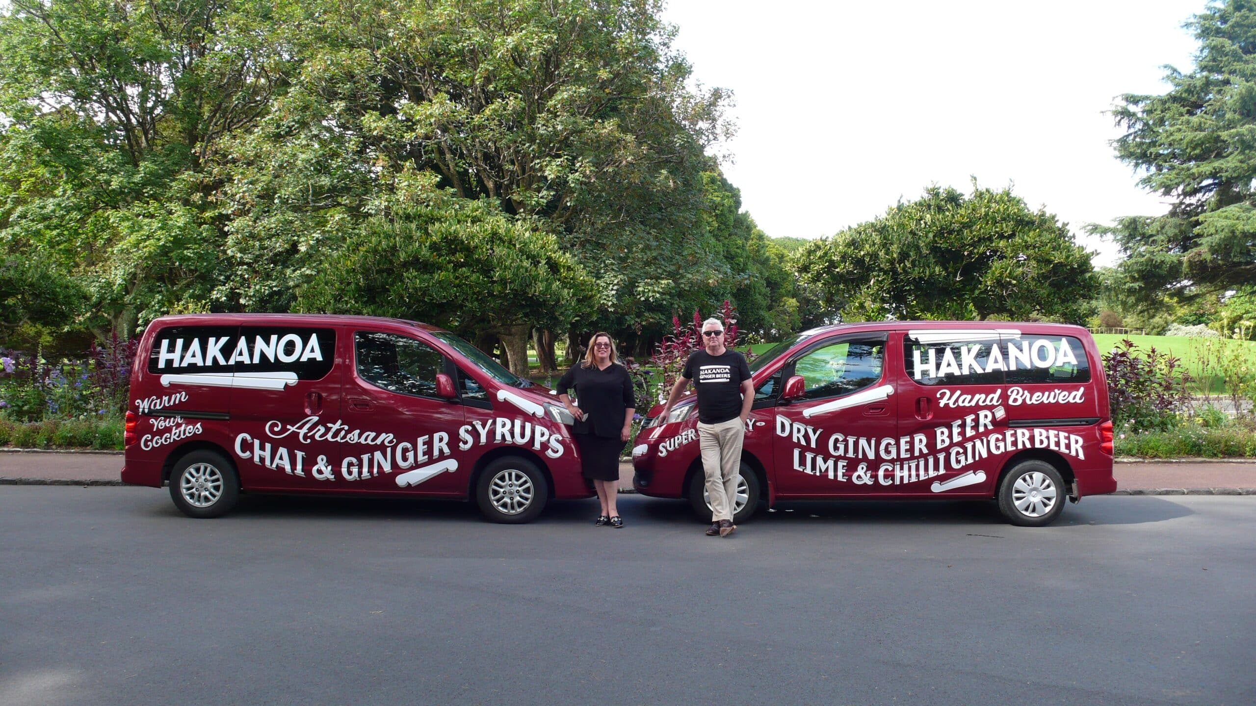 Two vans with Hakanoa branding on a road with trees in the background