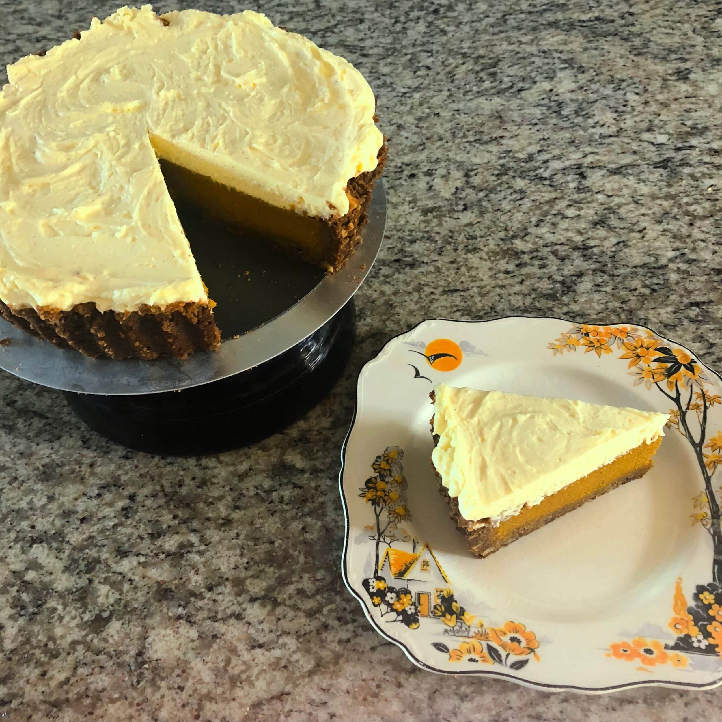 Cheesecake with a slice on a decorative plate on a granite countertop